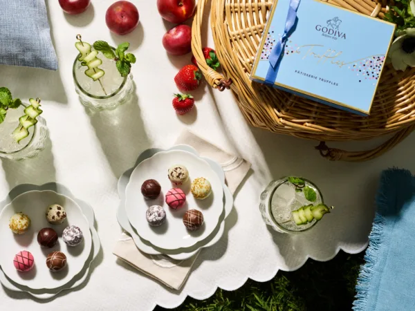 A beautifully styled springtime picnic scene with mojitos and Godiva truffles, showcasing prop styling by Elizabeth MacLennan and food styling by Liberty Fennell.