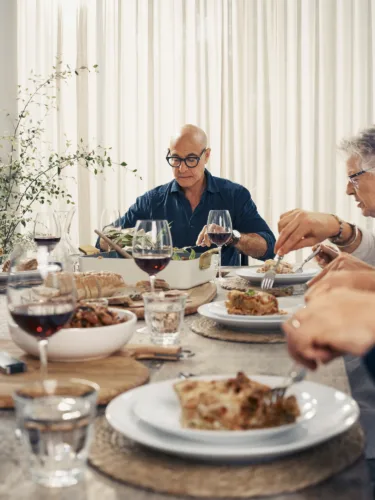 Lifestyle interior dining image of Stanley Tucci for Tucci x Green Pan x Williams Sonoma with prop styling by Elkie Brown, represented by Pat Bates & Associates, a premier agency in the retail home and lifestyle brand sectors.