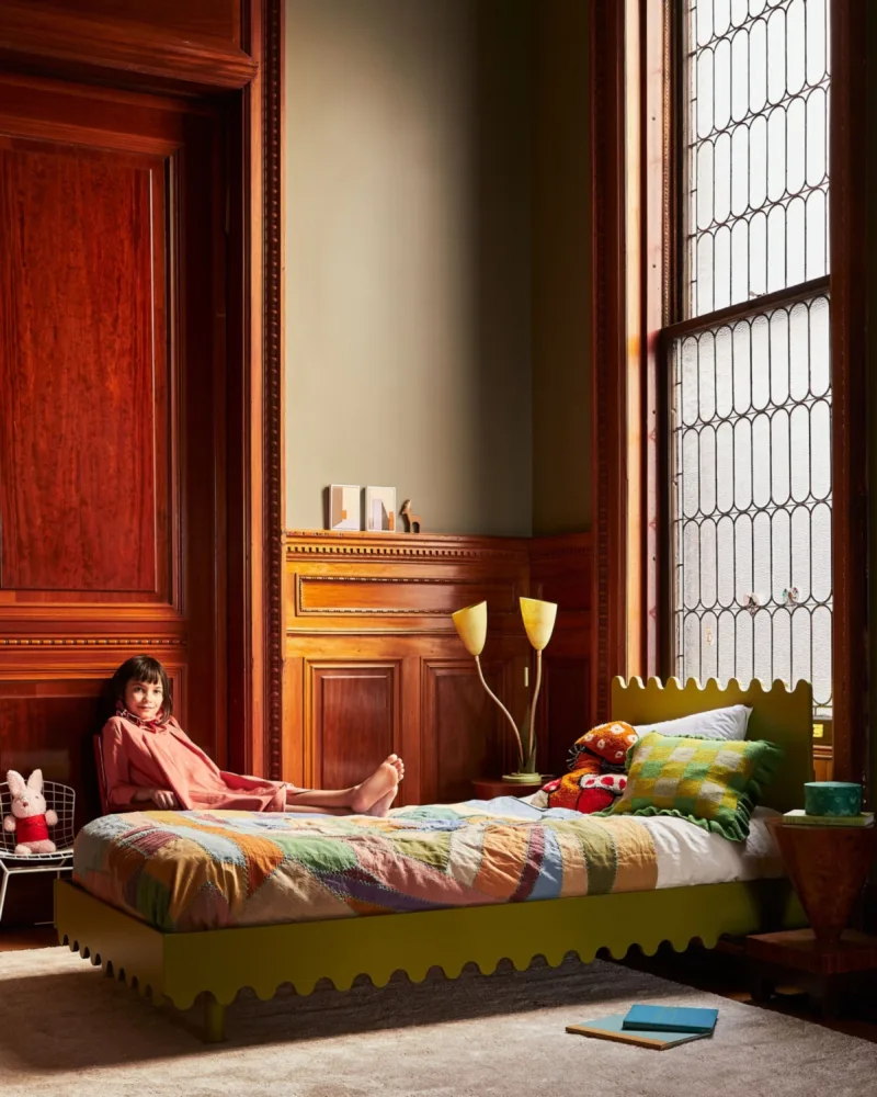 Lifestyle still interior image of young girl in bedroom for Oeuf by photographer Kate S. Jordan and prop stylist Naomi De Manana, represented by Pat Bates & Associates, a premier photo and artist agency in the kids home decor sector.