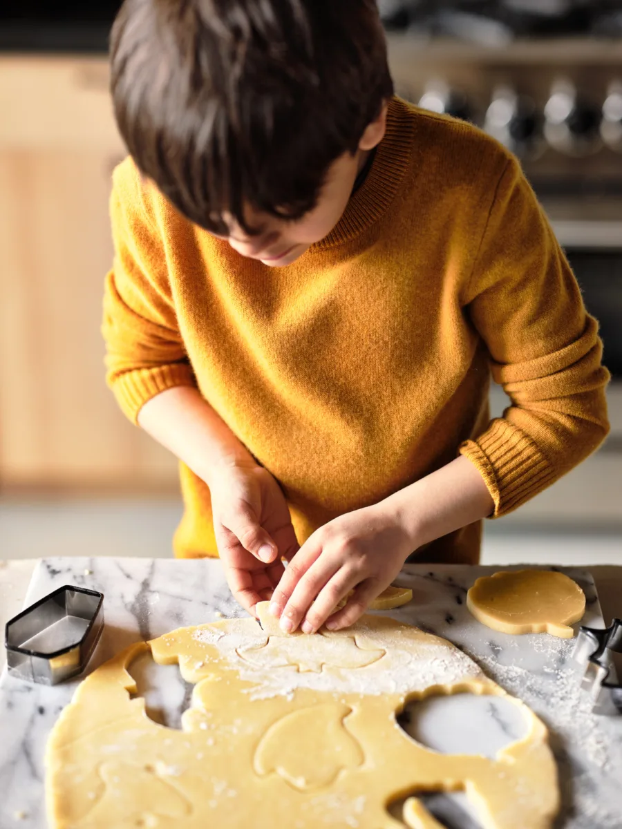 Lifestyle still image of child using cookie cutters for holiday baking for Crate & Barrel with prop styling by Lynsey Fryers, represented by Pat Bates & Associates, a premier photo and artist agency in the retail home brand sector.