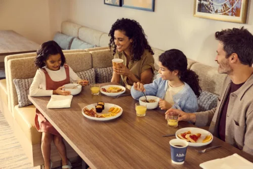 Interior still image of family enjoying a meal together for Hilton Homewood Suites – Las Vegas by photographer Toby Mitchell, represented by Pat Bates & Associates, a premier photo and artist agency in the travel and hospitality brand sectors.